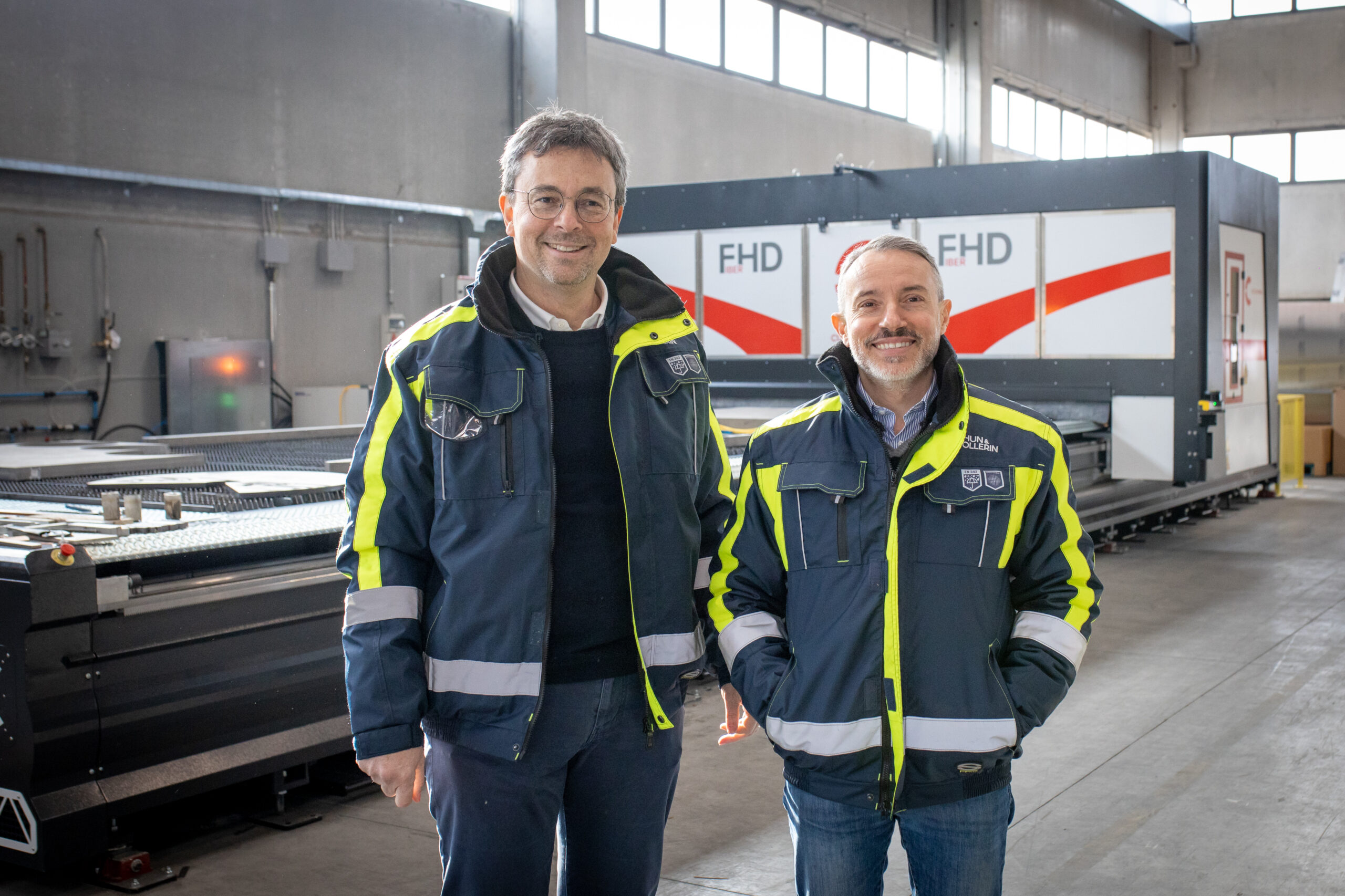 Zwei Verantwortliche von Chun & Vollerin in Arbeitsjacken vor dem FHD Faserlaser-Schneidsystem von Cutlite Penta im Werk in Cusago