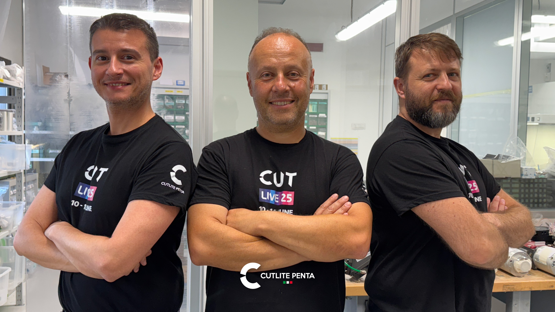 Drei Techniker der Schneidkopf-Abteilung von Cutlite Penta im CUTLIVE25-Shirt vor dem Reinraum, in dem die Laserschneidköpfe montiert werden