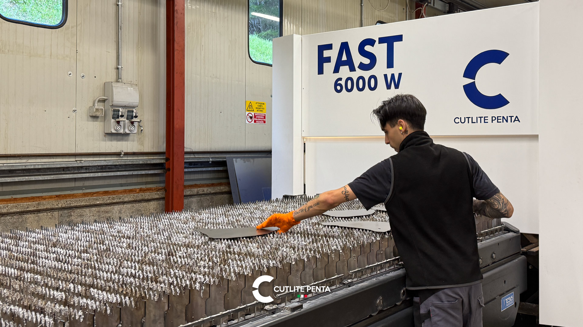 An operator lifting a cut part from the slats of Fratelli Martinelli's FAST 6000 W