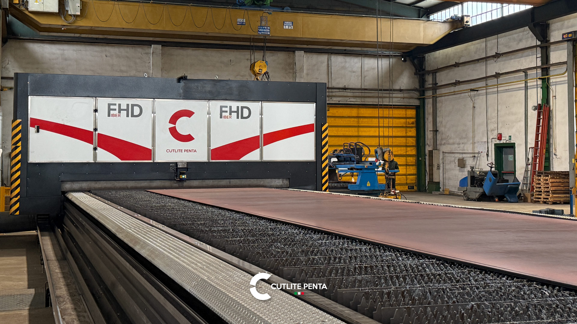 La mesa de la FHD de Nuova Lamierprofil con una chapa entera apoyada sobre las lamas, y el puente grúa encima