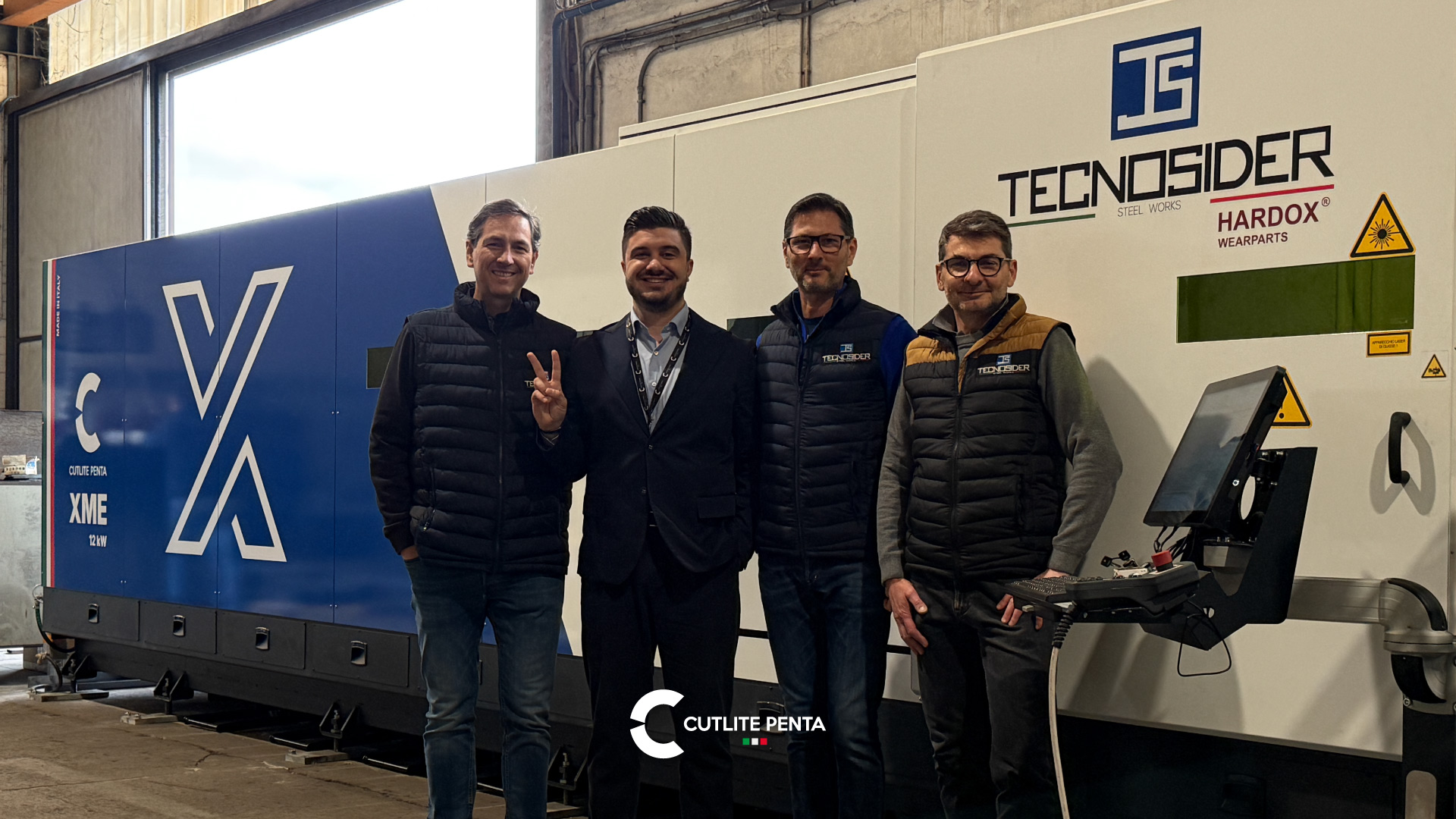 Four people in front of the XME 12 kW with the custom Tecnosider and Hardox Wearparts livery