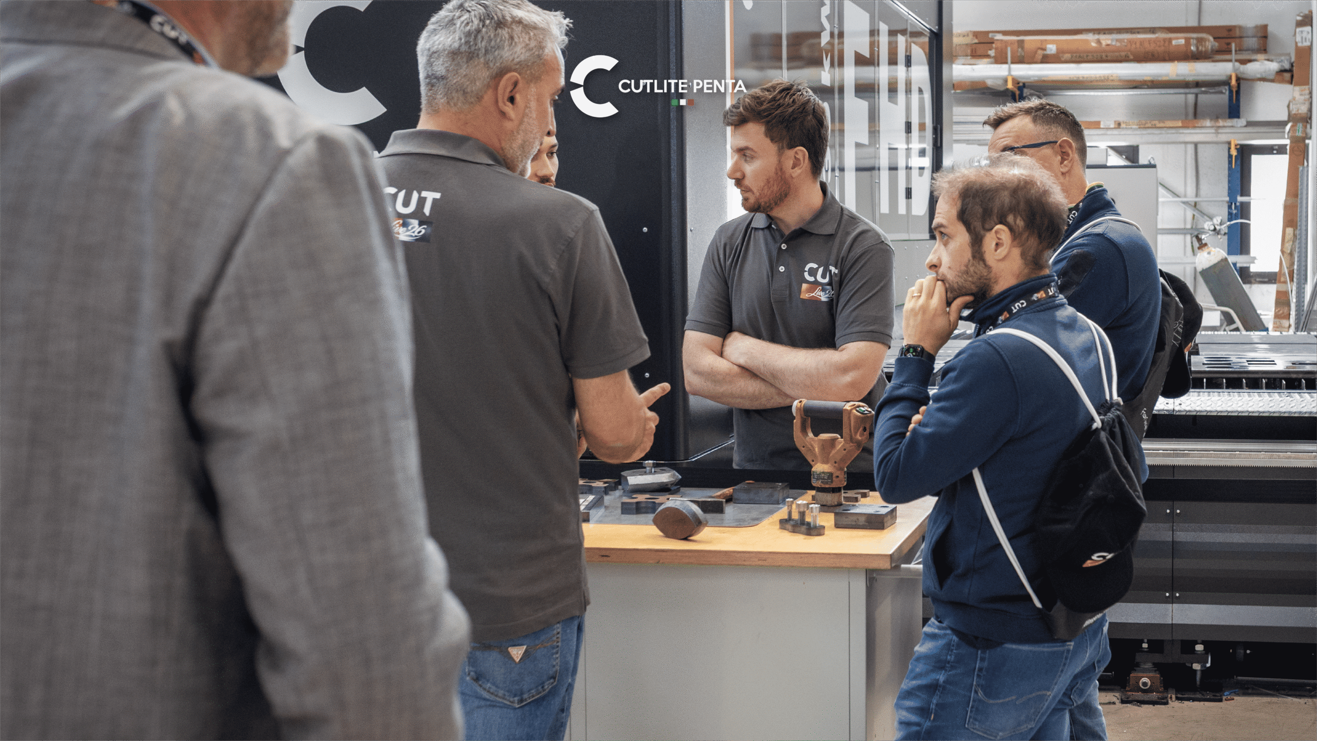 Visitatori di CUTLIVE26 a confronto con un tecnico Cutlite Penta attorno al banco con i pezzi tagliati, davanti alla FHD