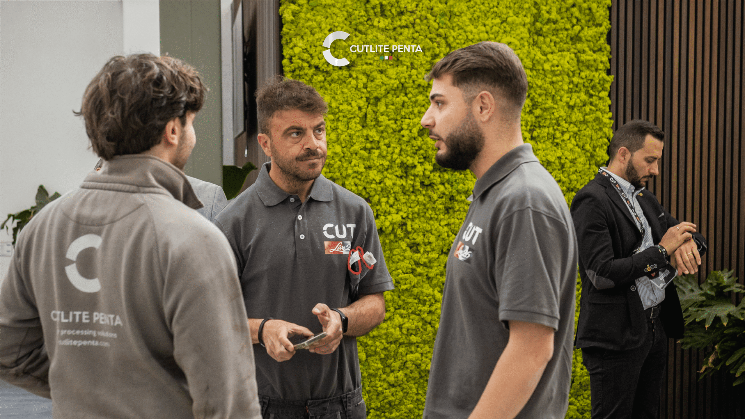 Momento di networking nella lobby di CUTLIVE26, con la parete verde e l'insegna Live26