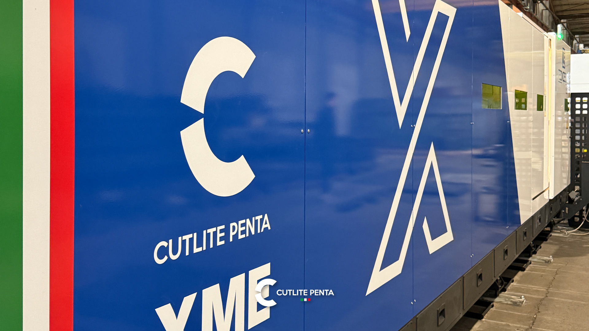 A lateral azul da XME 12 kW da Tecnosider com a pintura personalizada, o grande X branco e a faixa tricolor